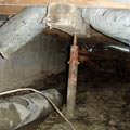 Rusty steel crawl space jack post supports in a structure in Webster.