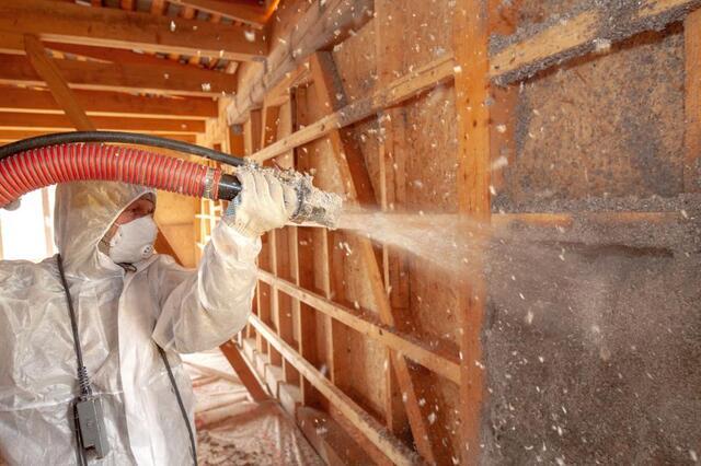 man putting in blown insulation in a home