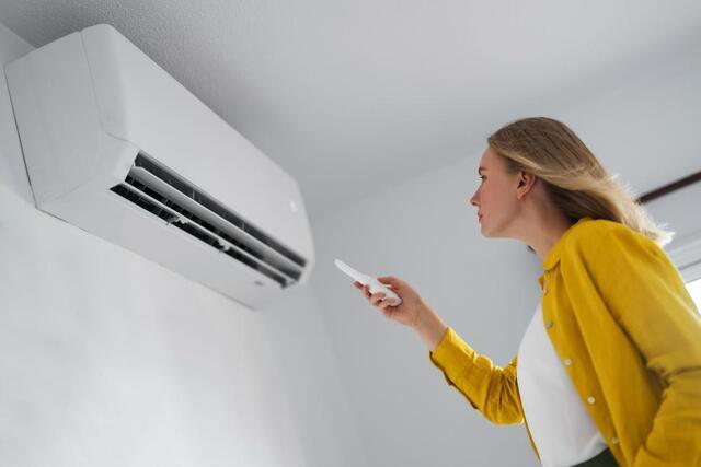 woman standing in front of a heat pump, staying cool