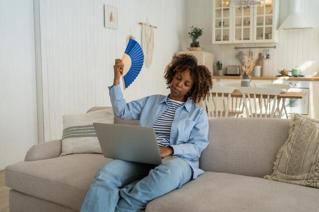 woman trying to get cool with a fan