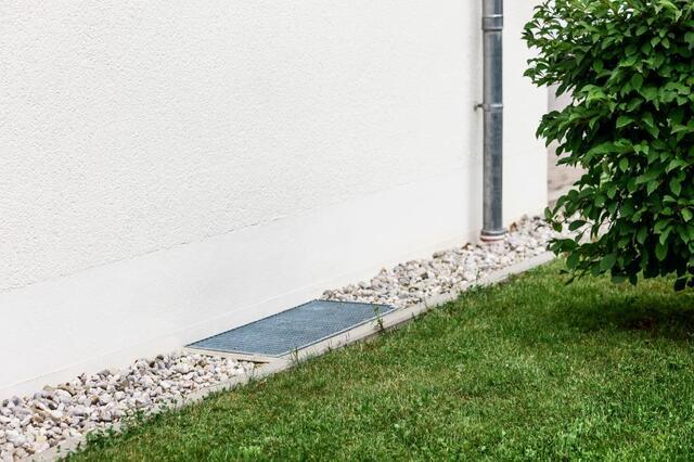 Drain Gravel Crushed Stones along Building Wall with Downspout