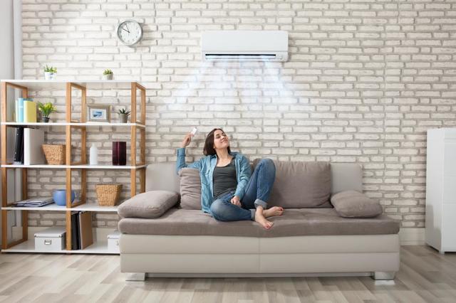 woman sitting on couch being cooled by a heat pump